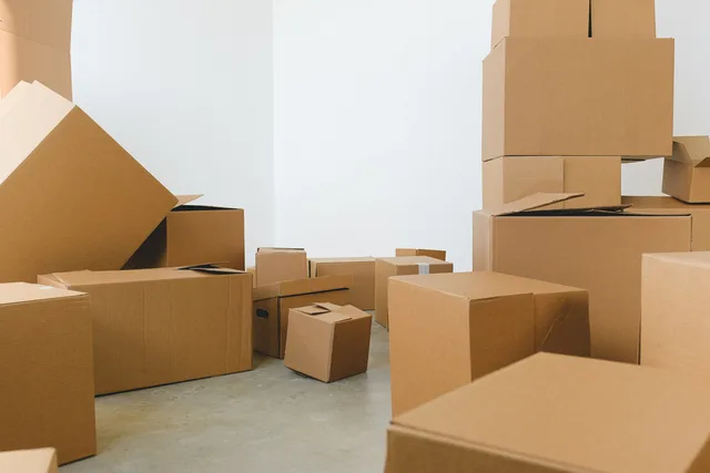 Stack of carton boxes of various shapes and sizes scattered in floor near white walls during relocation. Aligning billing dates with fulfilment cutoffs
